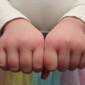 Lapsen kuivat kädet nyrkissä ojennettuna eteenpäin lähikuvassa.