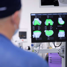 Ortopedi tutkii näytöltä 3D-kuvia leikkaussalissa.