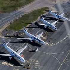 Aerial view of four white Finnair planes parked on a runway in bright weather with green grass in the background.