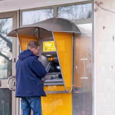 Mies asioi pankkiautomaatilla.