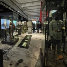 Ihmisiä kulkee museossa sisällissotaa esittelevien vitriinien keskellä.