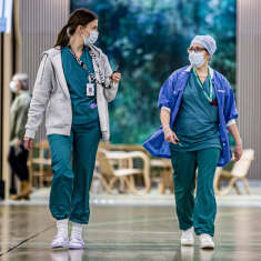 Kaksi hoitohenkilöä kävelee sairaalan käytävällä.