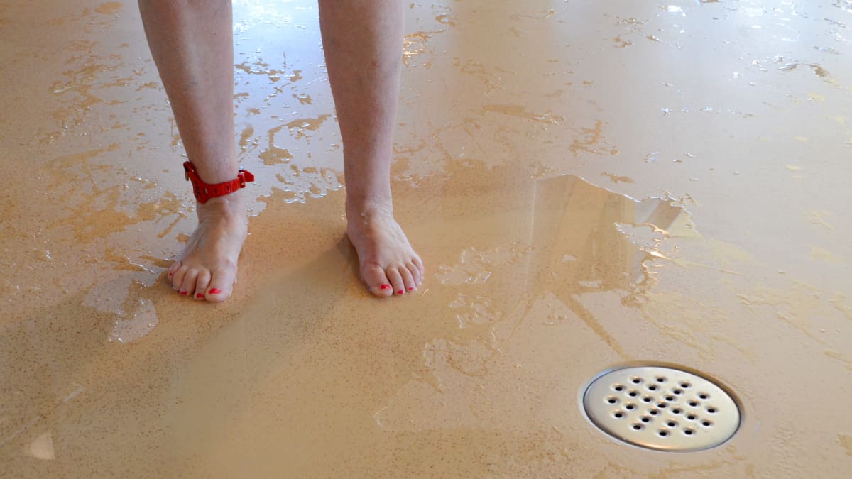Ett par fötter står i en vattenpöl i en simhall.