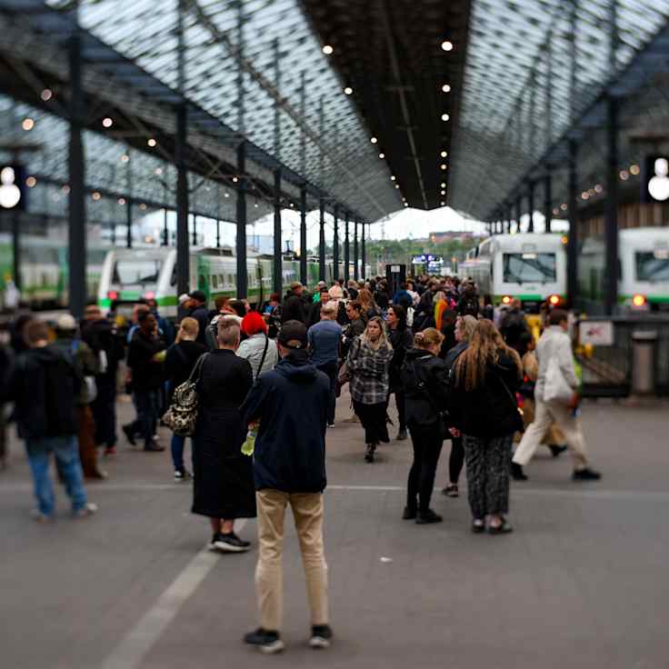 Männskor och tåg står på Helsingfors centralstation.