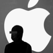 Henkilö seisoo Applen logon edustalla tunnistamattomana. 