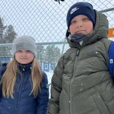 Biret-Elle Ruotsala ja Nils-Matti Paltto odottavat koulukyytiä, taksia lähellä Inari koulua 23.4.2024 Inarissa.