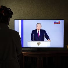 Nainen katsoo televisiosta, kun Venäjän presidentti Vladimir Putin pitää puhettaan Moskovassa 21. helmikuuta 2023.