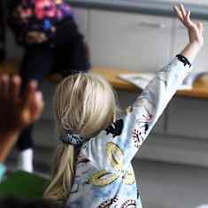 Koululaiset viittaavaat luokkahuoneessa.