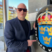 Risto Dufva seisoo Ruotsin konsulaatin kyltin vieressä.