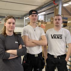 Essi Leminen, Wili Ojala ja Miika Mutka seisovat rakennusalan yrityksen varastossa työvaatteet päällä.