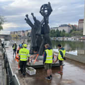 Maailman rauha -patsas siirrettiin proomuun Hakaniemenrannassa. Kuva patsas proomun kannella ja nostotyöntekijöitä sen ympärillä.