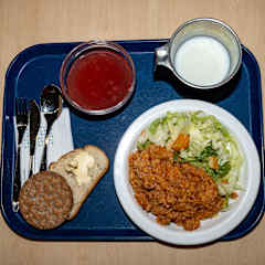 Tarjotinilla on Lautasen jossa kasvisrisottoa, lasi maito, leipä ja kiisseli.