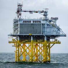 Energiaa tuottava asema luodolla meressä. Keltaiset rakennelmat tukevat teräksistä energialauttaa.