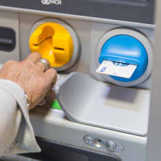 En person knappar in sin kod i en bankautomat.