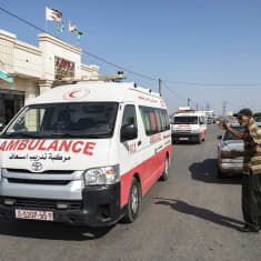 A thin elderly man stands in a road as ambulances with wounded Palestinians arrive at the Rafah border crossing between the Gaza Strip and Egypt.