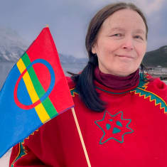 Astrid Båhl, saamenlipun suunnittelija kannattelee Saamen lippua.