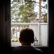 Lapsi katsoo ikkunasta ulos.