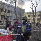 Raskaana olevaa naista kannetaan paareilla pommituksen tuhoaman sairaalan raunioista.