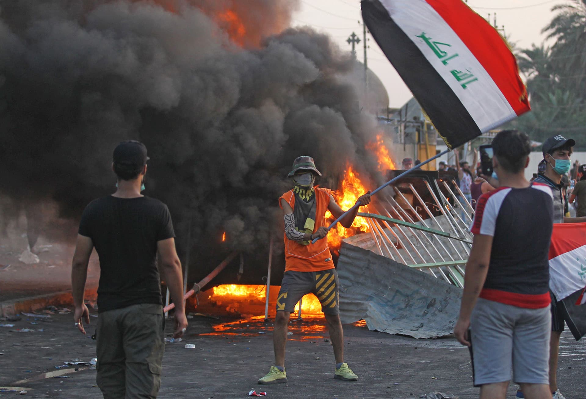 Mies heilutti Irakin lippua mielenosoituksessa Bagdadin Tayeranin aukiolla perjantaina.