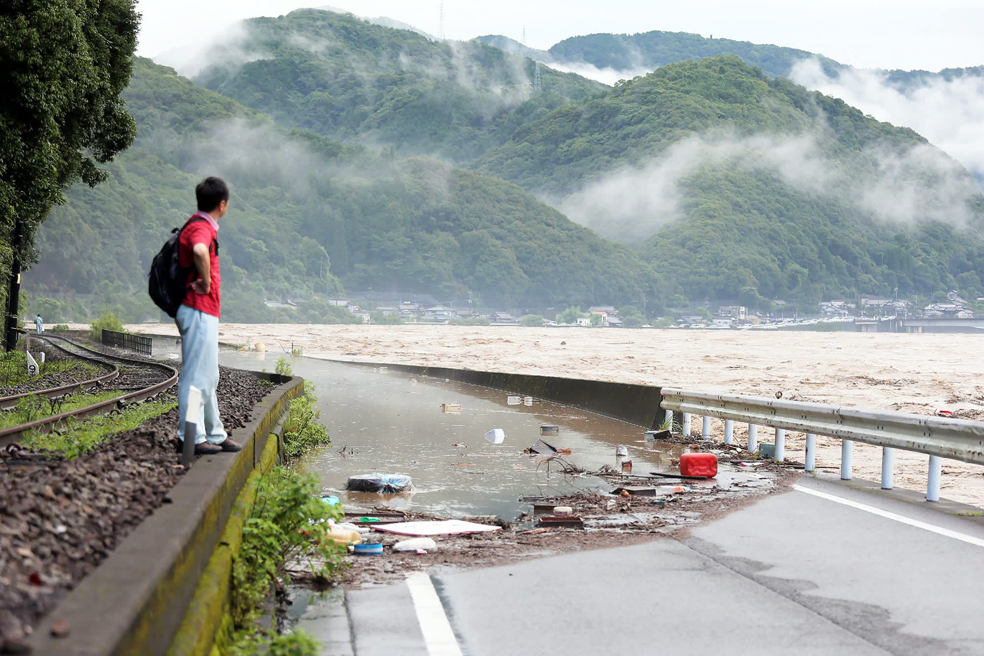 Mies katsoo tielle tulvinutta jokea Japanin Yatsushirossa