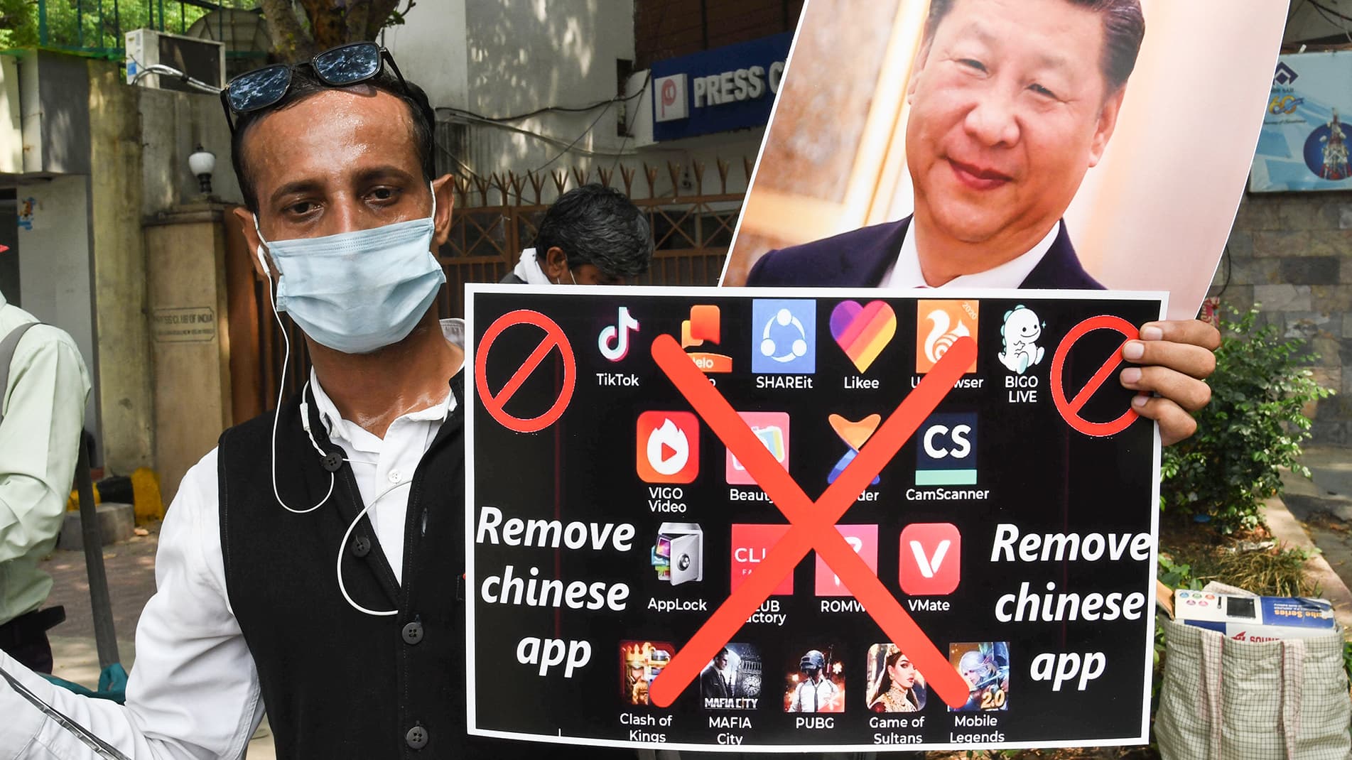 Mielenosoittaja pitää kiinalaisia sovelluksia vastustavaa kylttiä ja Kiinan presidentin kuvaa