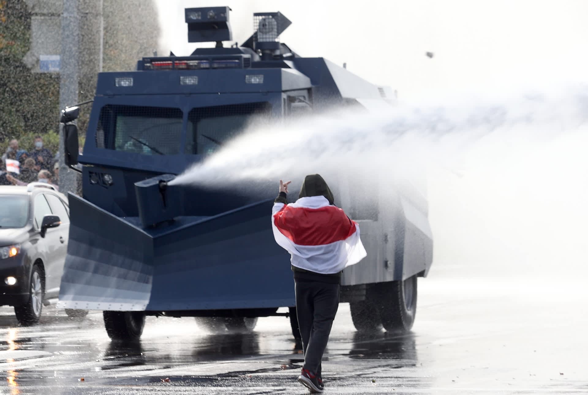 Valkovenäläinen mielenosoittaja uhmaa poliisin vesitykkiautoa.