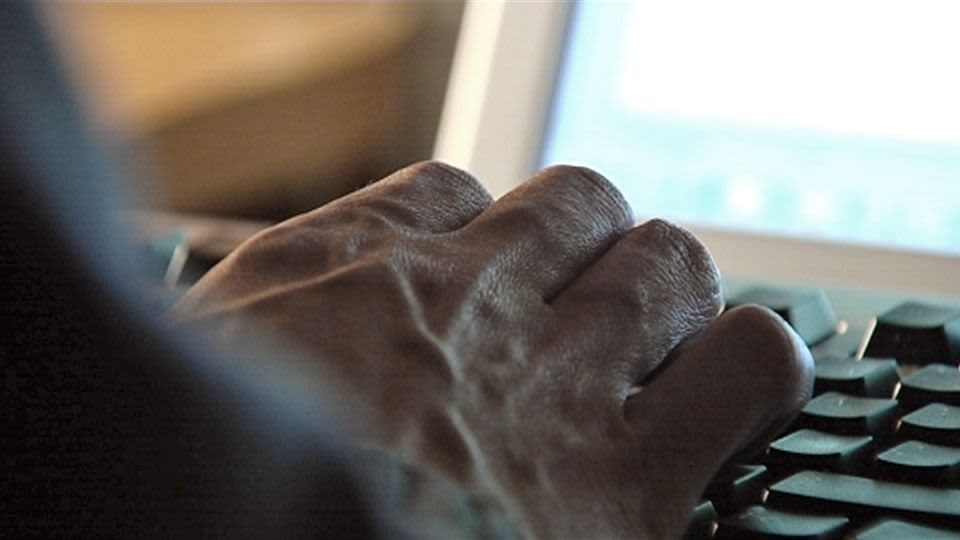 Miehen käsi tietokoneen näppäimistöllä.