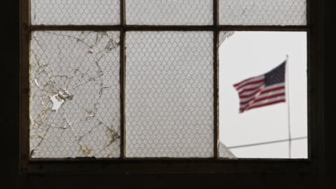 Guantánamon erään parakin kuusiosaisen ikkunan läpi kuvattu maisemanäkymä. Vasen lasi on rikkoutunut, oikeimmaisin lasi on kokonaan pois. Avonaisesta ikkunanäkymästä näkyy Yhdysvaltain lippu.