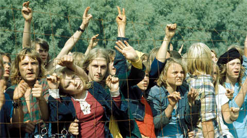 Vuoden 1974 Ruisrock-yleisö seuraa konserttia aidan takaa.