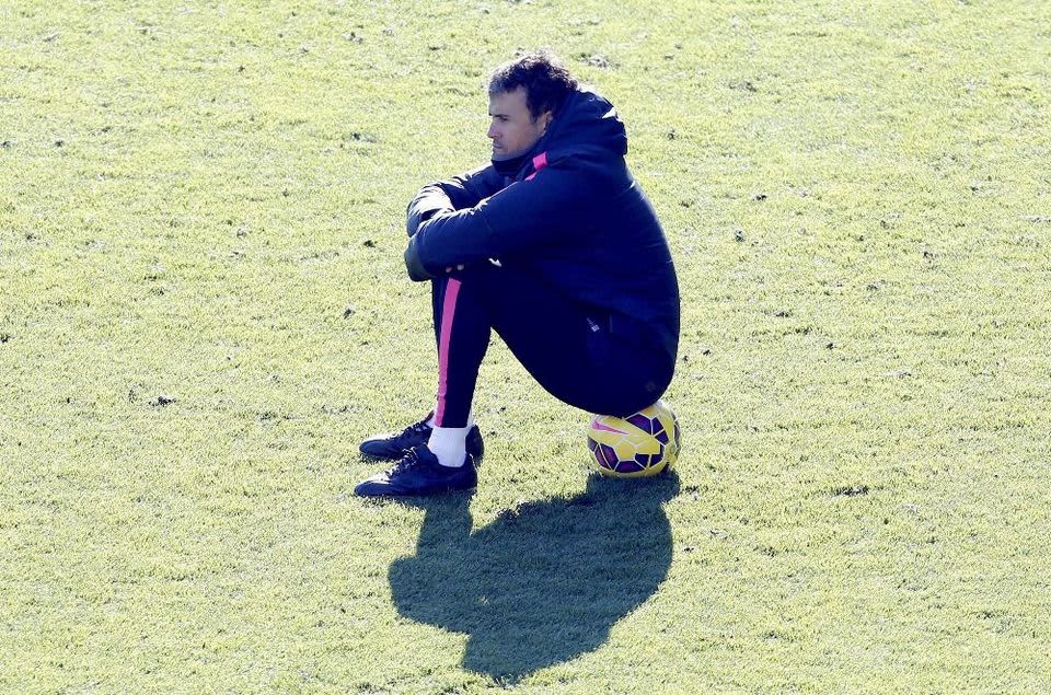 Barcelonan päävalmentaja Luis Enrique istuu pallon päällä.