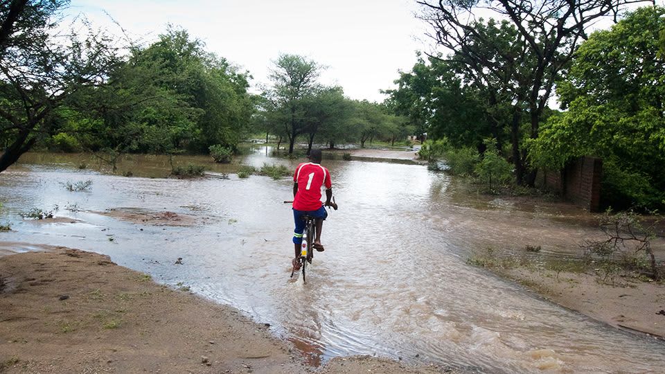 Malawialainen mies pyöräilee tulvavedessä Chikwawassa