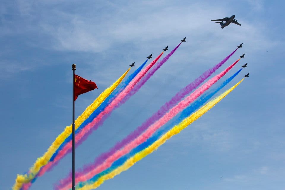 Sotilaskoneet piistävät taivaalle keltaisia, sinisiä, pinkkejä ja violetteja savujuovia. 