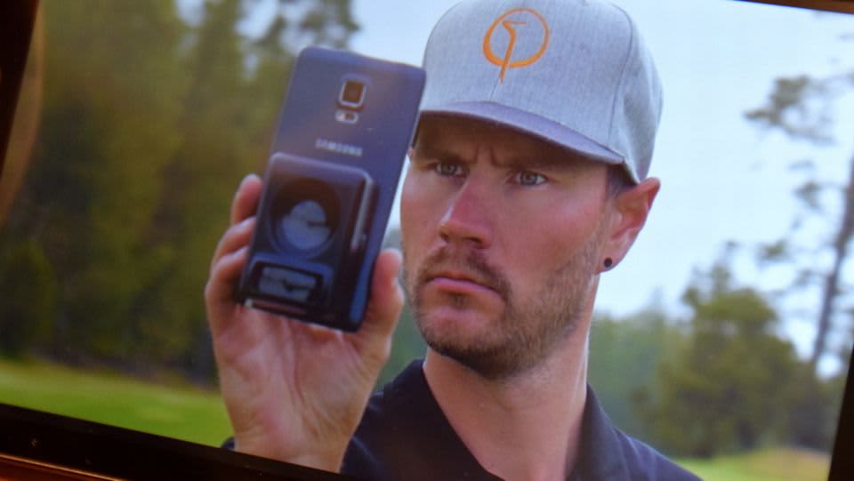 Mies käyttää kännykällään Caddieye-väylämittaria mainosvideolla