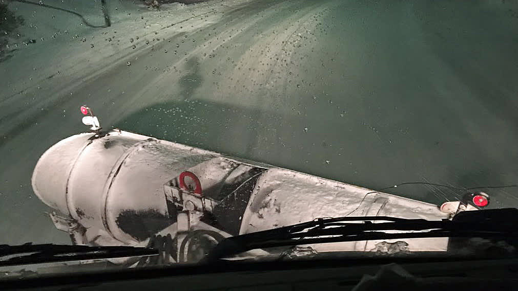 Näkymä lumiauran ohjaamosta lumiselle ajotielle.