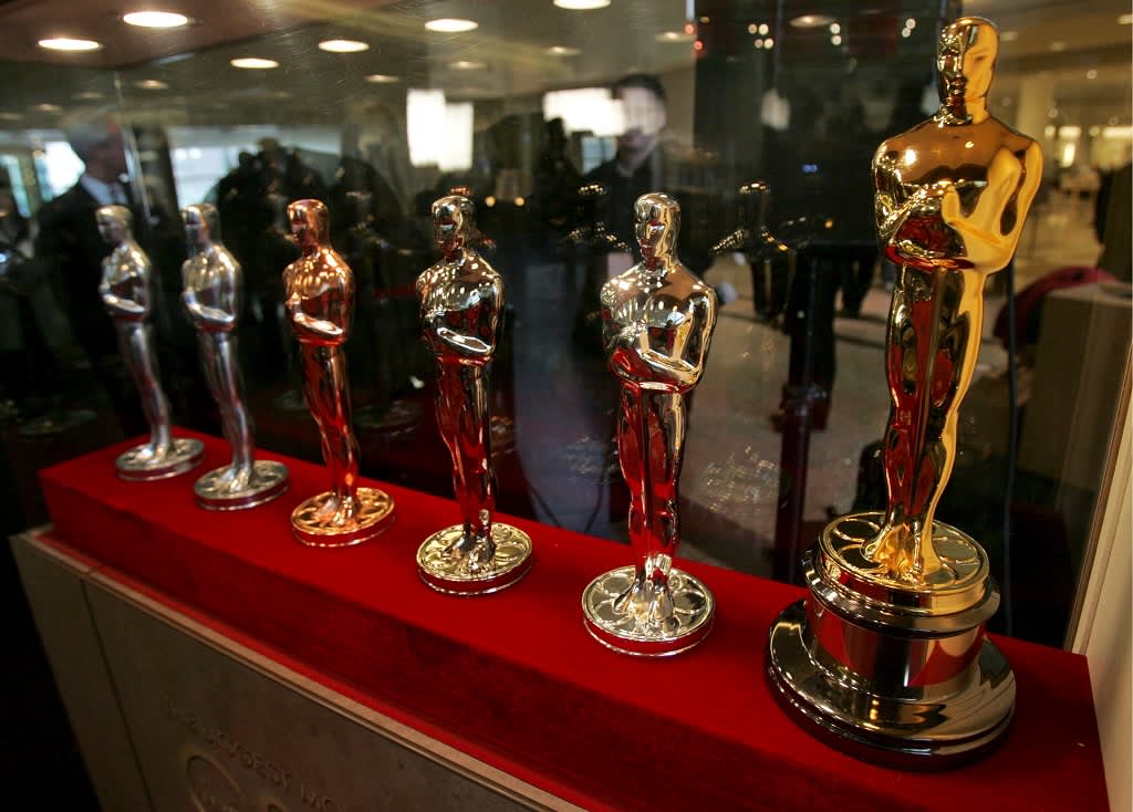 Kuusi Oscar-patsasta rivissä punaisella alustalla. Ensimmäinen on vasta ydin, viimeinen kullattu ja kiillotettu. 