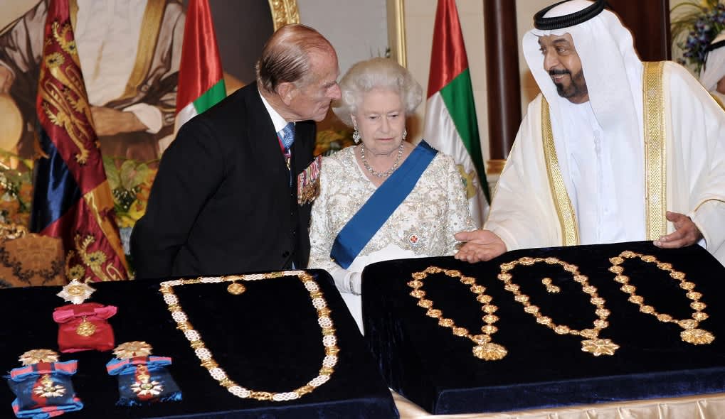 Sheikki Khalifa bin Zayed Al Nahyan esittelee kuningatar Elisabetille ja prinssi Philipille kolmea kaulaketjua ja kunniamerkkejä, jotka ovat samettialustalla. 