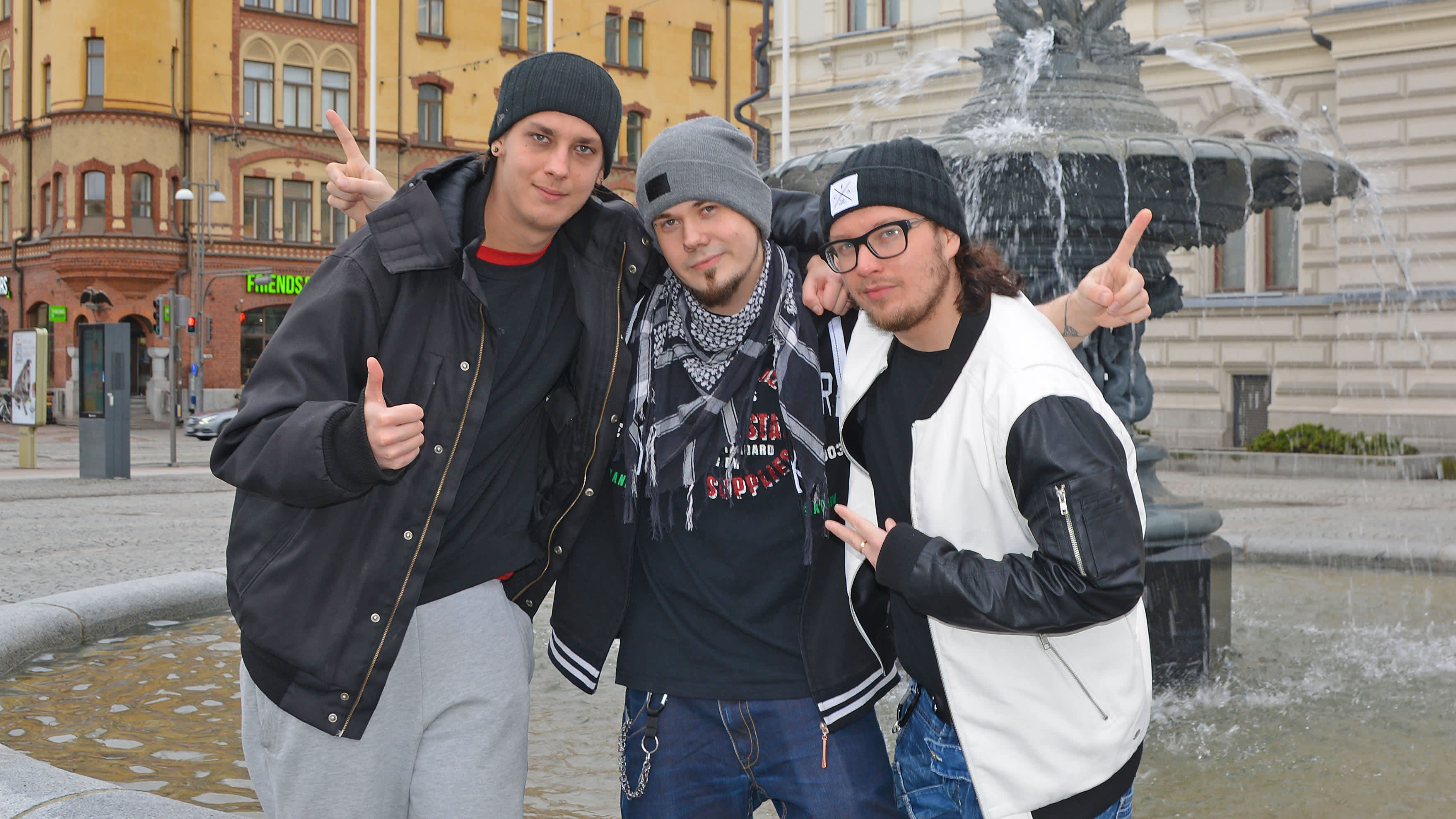 Rap-yhtye mansesterin jäsenet poseeraavat Tampereen keskustorilla suihkulähteen edessä.