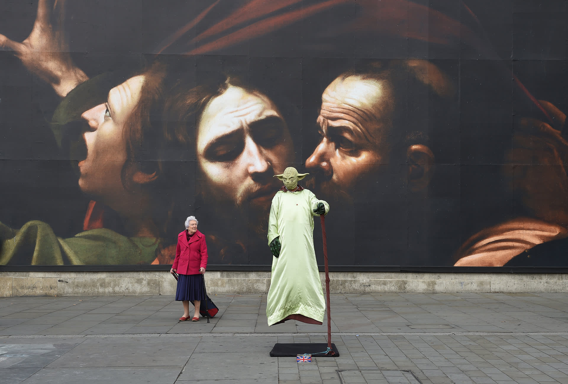 Yodan asuun pukeutunut katuesiintyjä valtavan Caravaggio -julisteen edessä Lontoossa 12. lokakuuta.