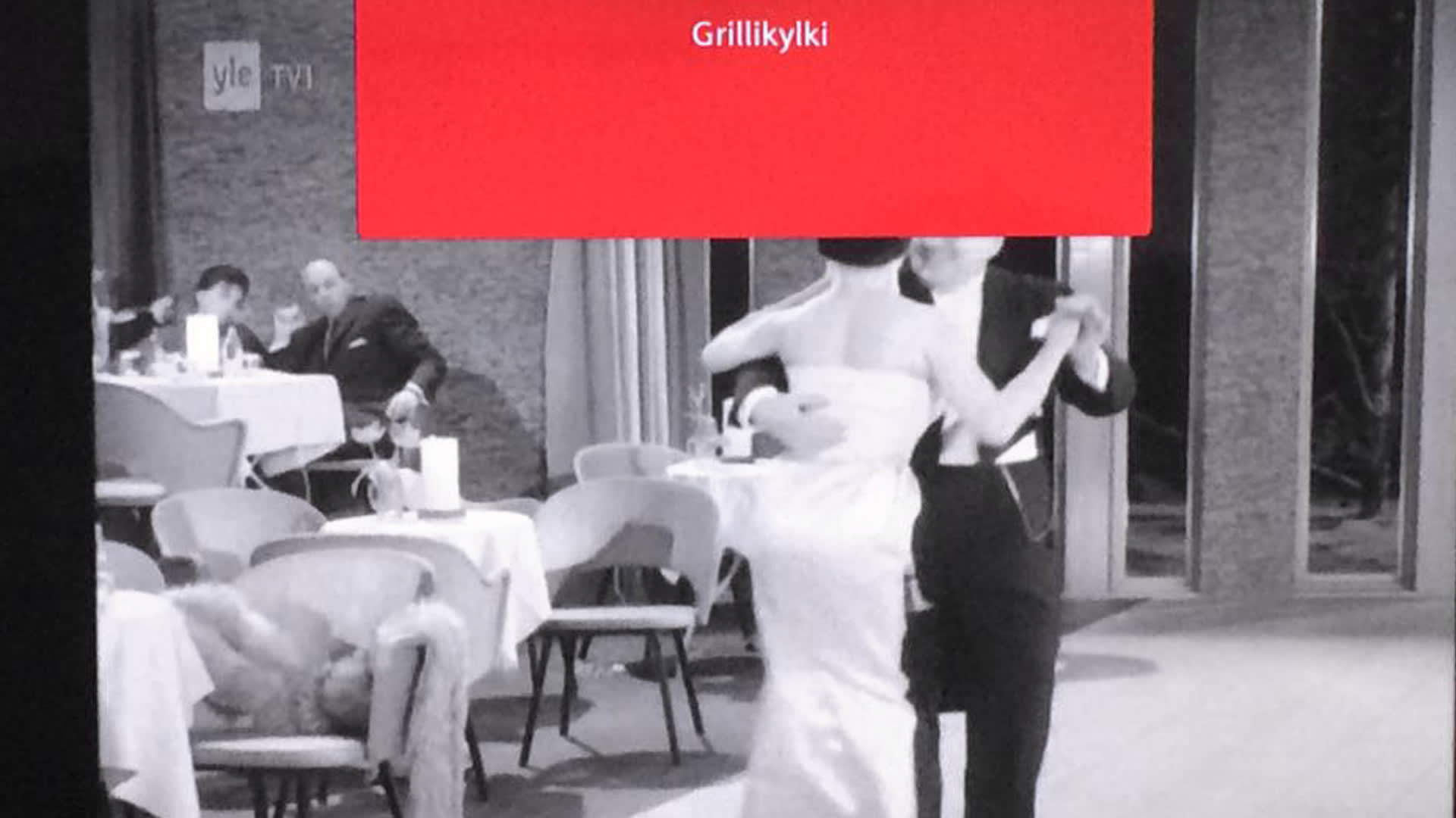 Tv-kuva, jossa näkyy teksti "grillikylki" sekä kuvassa tanssijoita. 
