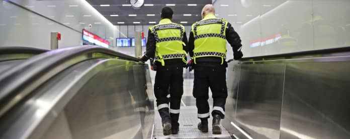 Kaksi vartijaa metroaseman liukuportaissa.