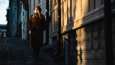 Nainen hengitysmaski kasvoilla kävelee Puu-Vallilassa.
