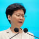 Carrie Lam puhuu mikrofoneihin. Tausta on vaaleansininen.