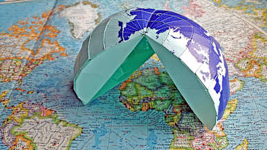 Japanilainen AuthaGraph-origamikartta puoliksi koottuna. Alla vanha karttakirja.