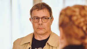 Ville Sandqvist är regissör och dramaturg samt vice dekan vid Teaterhögskolan i Helsingfors. För honom var berättelserna om Koivistos somrar och fritid i Täkter något helt nytt. En allvarlig glasögonprydd man tittar och lyssnar på en kvinna som står med ryggen vänd mot kameran.