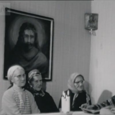 Vienankarjalaiset viettävät joulua, vasemmalla kolme iäkkäämpää naista ja kynttilöitä, oikealla nainen istuu saman pöydän ääressä selkä kameraan. Pöydän päässä istuu lukeva mies.