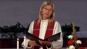 Liturg Hanna Eisentraut-Söderström Liturgen Hanna Eisentraut-Söderström läser en text vid altaret och ser ut mot församlingen i Borgå kyrka. Liturgiska färgen på stolan är röd.
