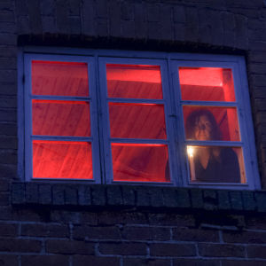 Toimittaja Kaisa Pulakka ullakkohuoneessa kynttilänvalossa ikkunan edessä