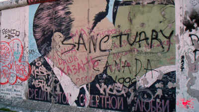 Graffititäckt bild på Brezjnevs och Honeckers broderskyss på Berlinmuren