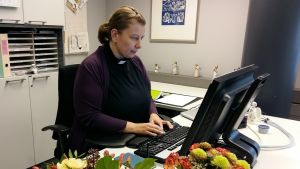 Mia Bäck i sitt arbetsrum i Aurelia i Åbo. Mia Bäck sitter vid sitt arbetsbord och skriver på datorn.