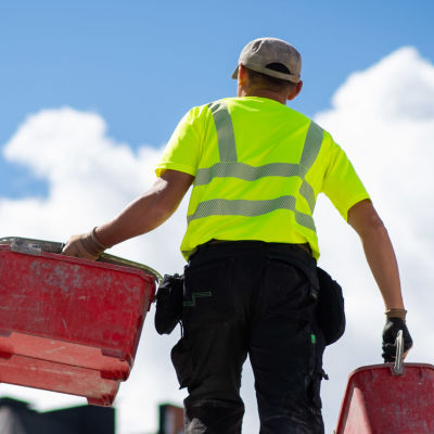 En man som jobbar vid en byggarbetsplats bär på två ämbare.